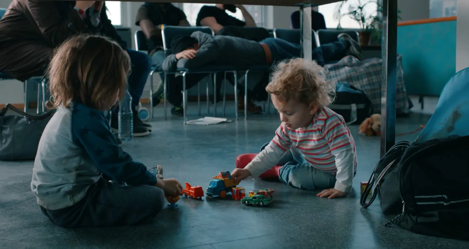 Small children playing with toys on the floor of a refugee shelter