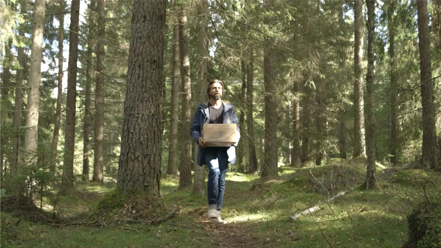Man carrying a box through a forest, from Mjau's campaign For Every Cat